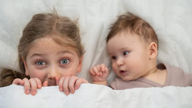 Top view of a little boy and his six year old sister lying under a blanket