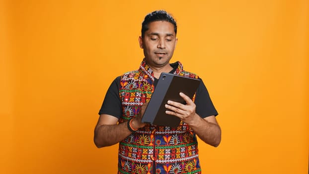 Man shakes head in disbelief after realizing lack of necessary funds while trying to shop online on tablet. Disappointed indian person gets credit card transaction rejected, studio backdrop, camera B