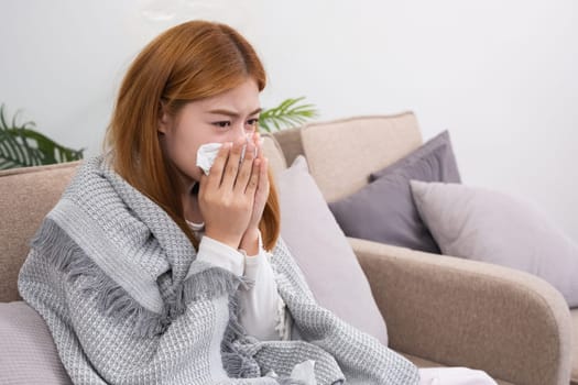 Young Asian woman with cold and allergies feels sick and sneezes on a day of resting at home..