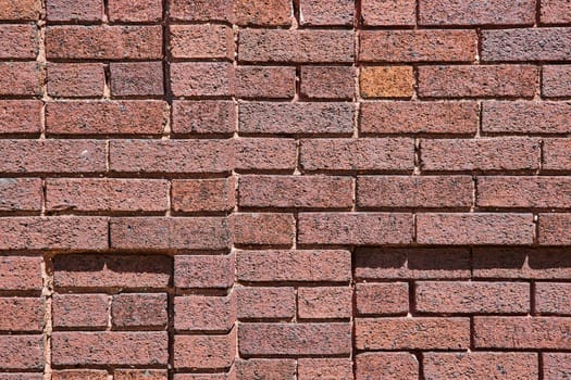 Close-up of a textured brick wall in Fort Wayne showcasing vibrant reds and detailed craftsmanship.