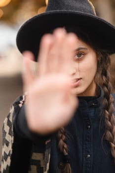 A chic girl in bohemian attire, accessorized with a black hat, enjoys the autumn ambiance of the city. High quality photo