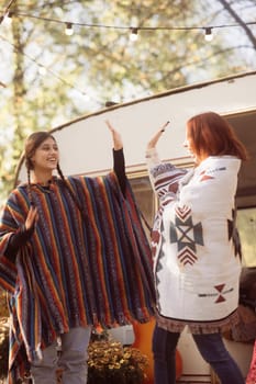 A couple of stylish ladies strike poses in their hippie ensembles near a trailer. High quality photo