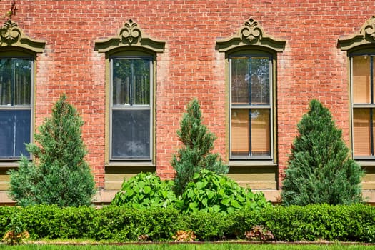 Historic red brick home in Fort Wayne, adorned with lush greenery and classical architecture.