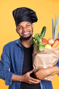 African american happy chef cooking a vegan meal with bio produce, shopping for organic groceries to prepare a recipe. Confident excited cook advertising ethically sourced food. Zero waste.