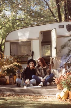 A pair of trendy gals don boho-chic attire against the trailer backdrop. High quality photo