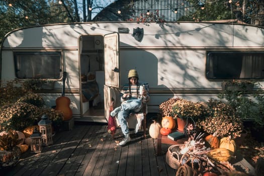 A stunning young woman embraces hippie fashion with a trailer as her backdrop in the park. High quality photo