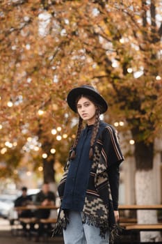 An enchanting woman, exuding boho style, wears a black hat as she strolls through the fall city streets. High quality photo