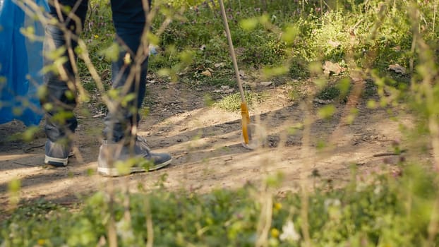 Diverse people working as activists to clean the forest from junk, fighting illegal dumping to protect the natural environment. Volunteers collecting rubbish, using tools to grab trash. Camera A.