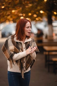 An exuberant redhead glows with laughter, enlivening the autumn city scene. High quality photo