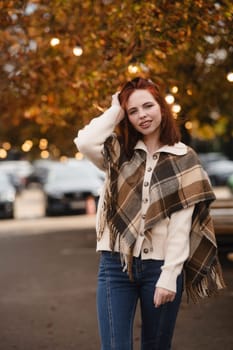 A cheerful redhead beams with joy on the streets of the autumn city. High quality photo