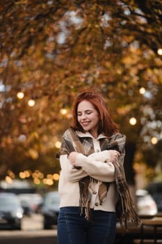 A joyful redhead brightens the autumn cityscape with her infectious smile. High quality photo