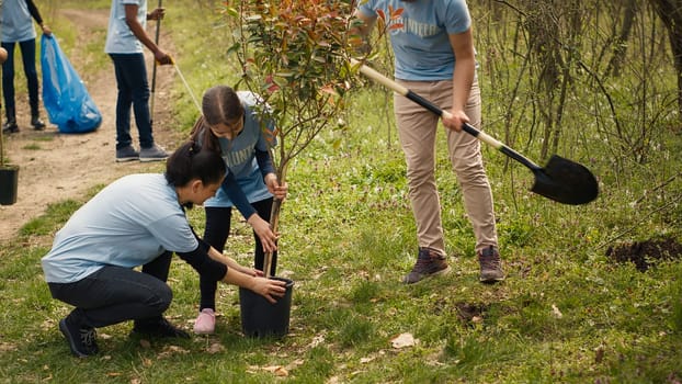 Team of volunteers planting trees around forest area for nature preservation and protection, doing voluntary work for a conservation project. Climate change activists plant seedlings. Camera A.