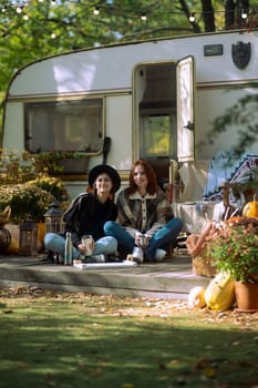 A duo of chic ladies flaunt their bohemian flair in front of the trailer. High quality photo