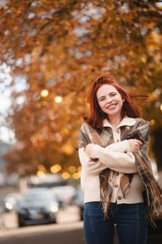 A vibrant red-haired lady laughs heartily, bringing cheer to the autumn city. High quality photo