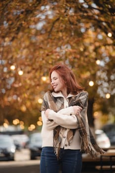 A lively redhead grins with delight, spreading warmth on the autumn streets. High quality photo