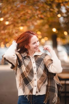 A sunny red-haired woman giggles with glee, infusing the autumn city with joy. High quality photo