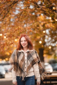 A delightful redhead smiles brightly, adding a touch of happiness to the autumn streets. High quality photo