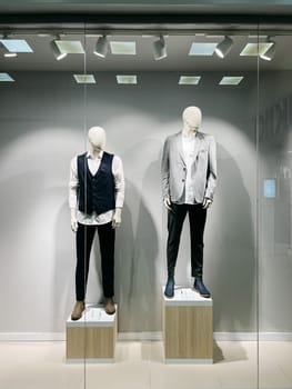 Mannequins with classic men clothing stand in a shop window. High quality photo