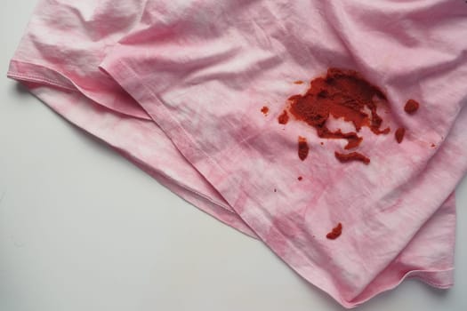 Tomato sauce spilled on gray color shirt. Food stain on shirt.