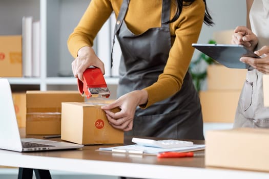 Young business entrepreneur sealing a box with tape. Preparing for shipping, Packing, online selling, e-commerce concept.