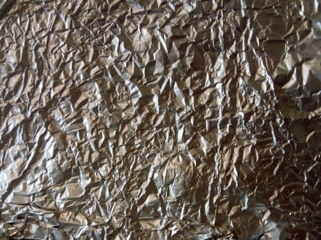 A Thin Leaf on a Silver Leaf Background with a Shiny, Wrinkled, Uneven Surface. Picture of Horizontal Aluminum Paper Crease.