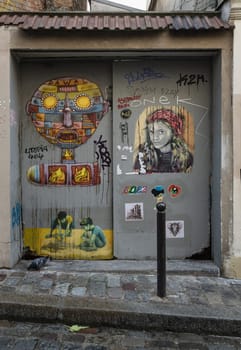 France, Paris - Jan 03, 2024 - A artistic metal doorway stickers and graffiti on Montmartre Street. Street art in Paris, Urban intervention art, Paris wall art, Space for text, selective focus.