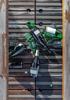 France, Paris - Jan 03, 2024 - Top view of The beer and wine bottles were left on the floor next to the wooden benches on Pont des arts. Light and Shadow, Space for text, Selective focus.