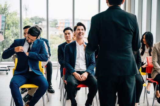 A young man raises his hand in a conference among peers demonstrating active engagement teamwork and a willingness to contribute to discussions.