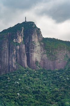 Christ the Redeemer statue in Rio stands amid a forest with ominous clouds overhead.