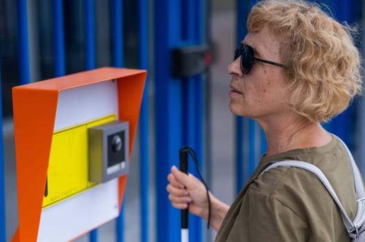 An elderly blind woman reading a text in braille. Button for calling help for people with disabilities