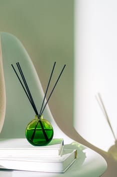 Liquid home perfume in glass diffuser with sticks on chair close up