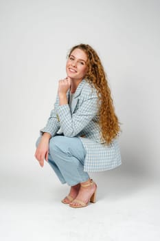 Young woman with curly hair in blue jacket posing on gray background close up