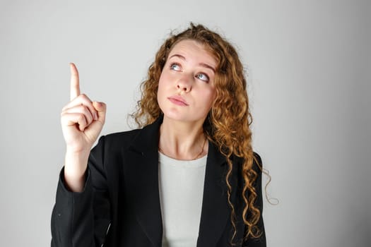 Young Woman in Black Jacket Pointing Up in Studio