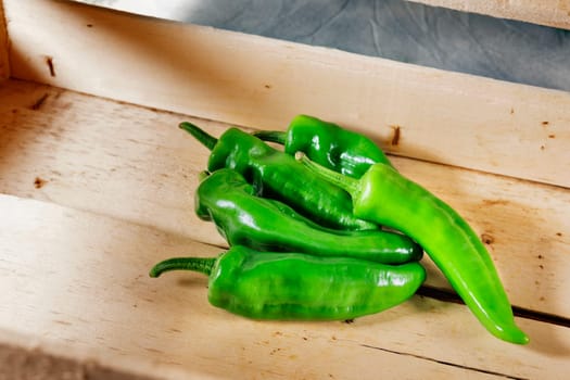 Sweet green chili peppers also known as the golden Greek pepper or Tuscan pepper in wooden crate,used as ingredient in salads and compotes
