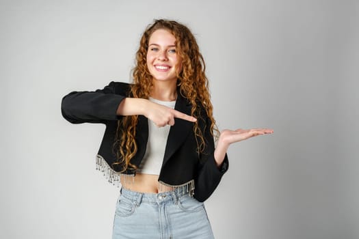 Smiling Young Woman Pointing While Posing in a Studio close up