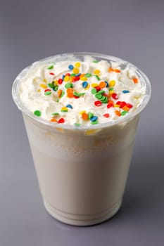 white milkshake with multicolored balls on a gray background.