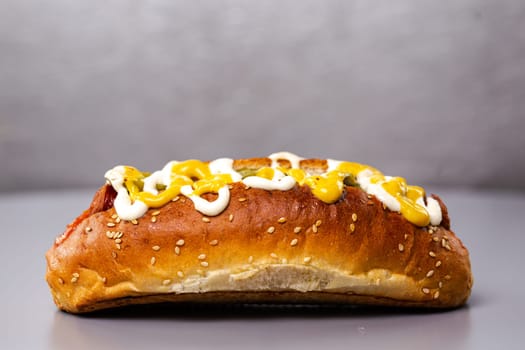 hotdog with sausage and sauce on a gray background.