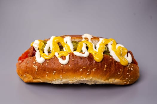 hot dog with sausage with mustard and mayonnaise on a gray background.