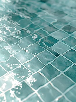 A closeup of a rectangular swimming pool with azure blue tiles and electric blue water reflecting the sky. The flooring is a mesh pattern of glass tiles, giving it an aqua appearance