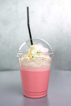 pink milky-pink cocktail in a plastic cup with a straw.