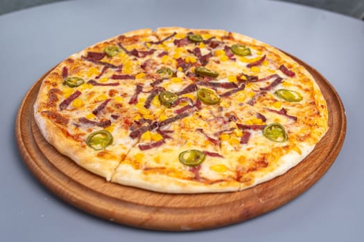 pizza with peppers and sausages on a wooded board.