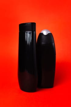 Two black plastic bottles on a red background.