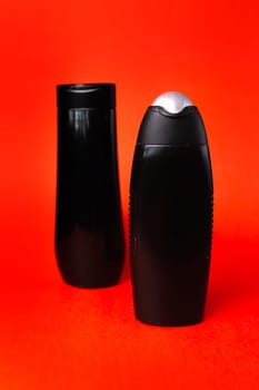 Two black plastic bottles on a red background.