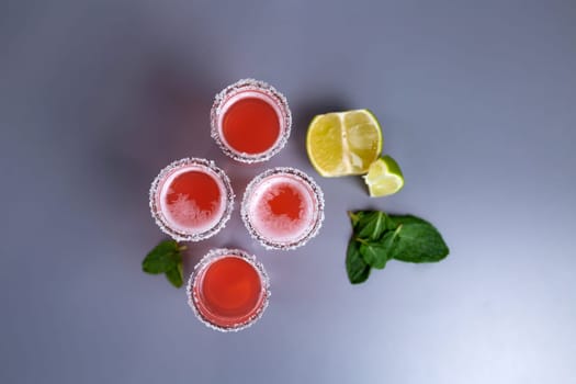 four pink cocktails with lime and mint top view.