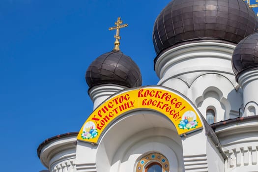 Shot of the domes of the orthodox church. Easter greetings written on Russian at the entrance