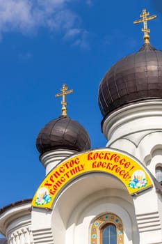Shot of the domes of the orthodox church. Easter greetings written on Russian at the entrance