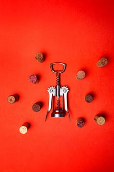 metal corkscrew with wine corks on a red background.