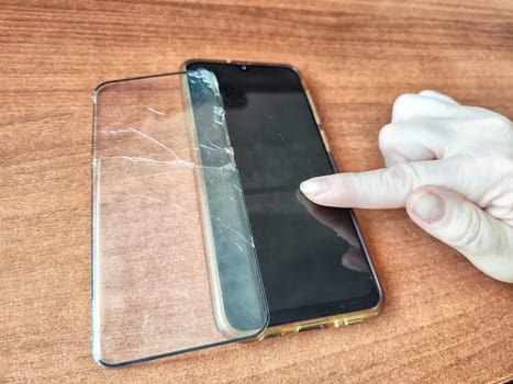 Removing Protective Film From Cracked Screen. Peeling off a cracked screen protector from a phone