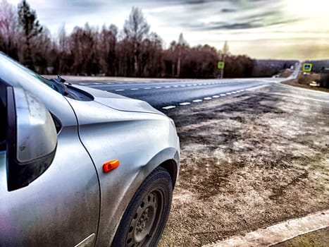 The car is on the side of the road. The concept of travel. A silver car stopped by the highway as daylight breaks