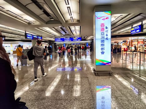 Hong Kong, China - April, 05, 2024: People walking through a busy terminal corridor at Hong Kong Airport